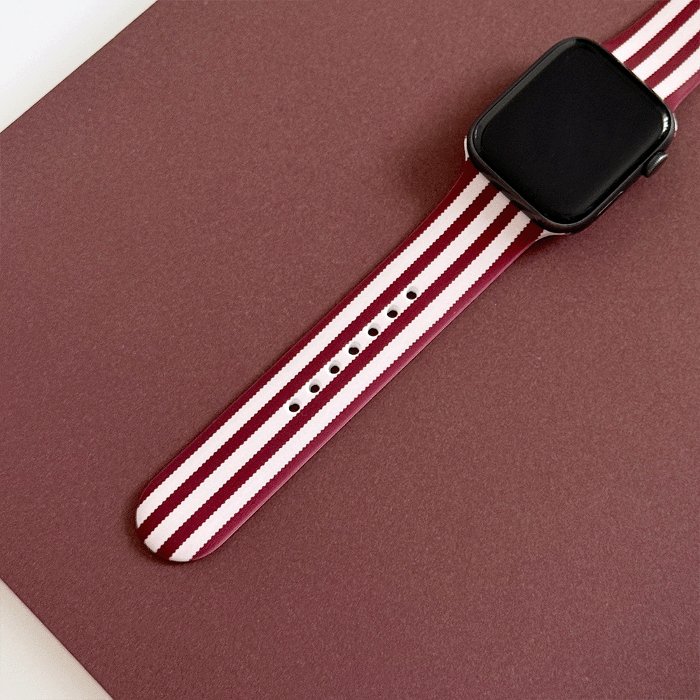 Burgundy and light pink striped Apple Watch Strap, attached to a black Apple Watch.