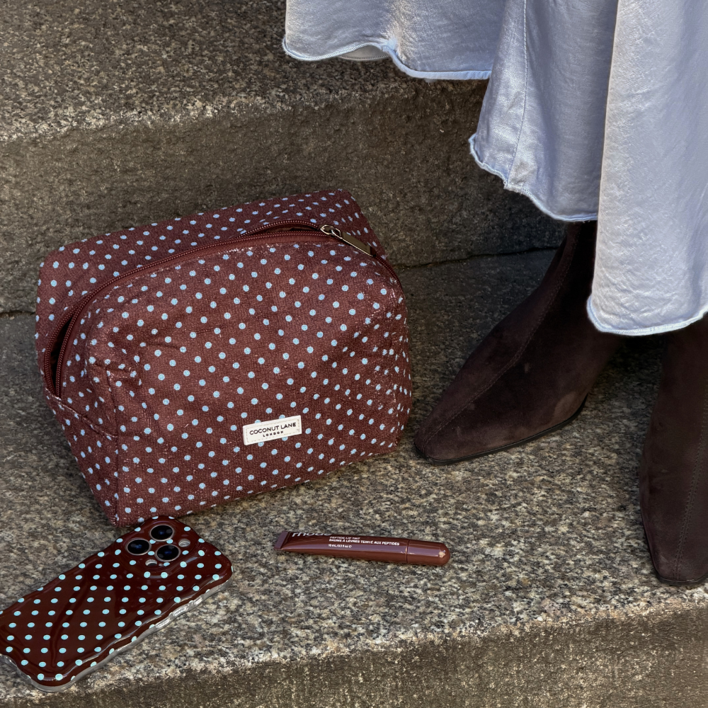 Girl stood on step in brown heels next to the brown and blue towel makeup bag and wavy phone case