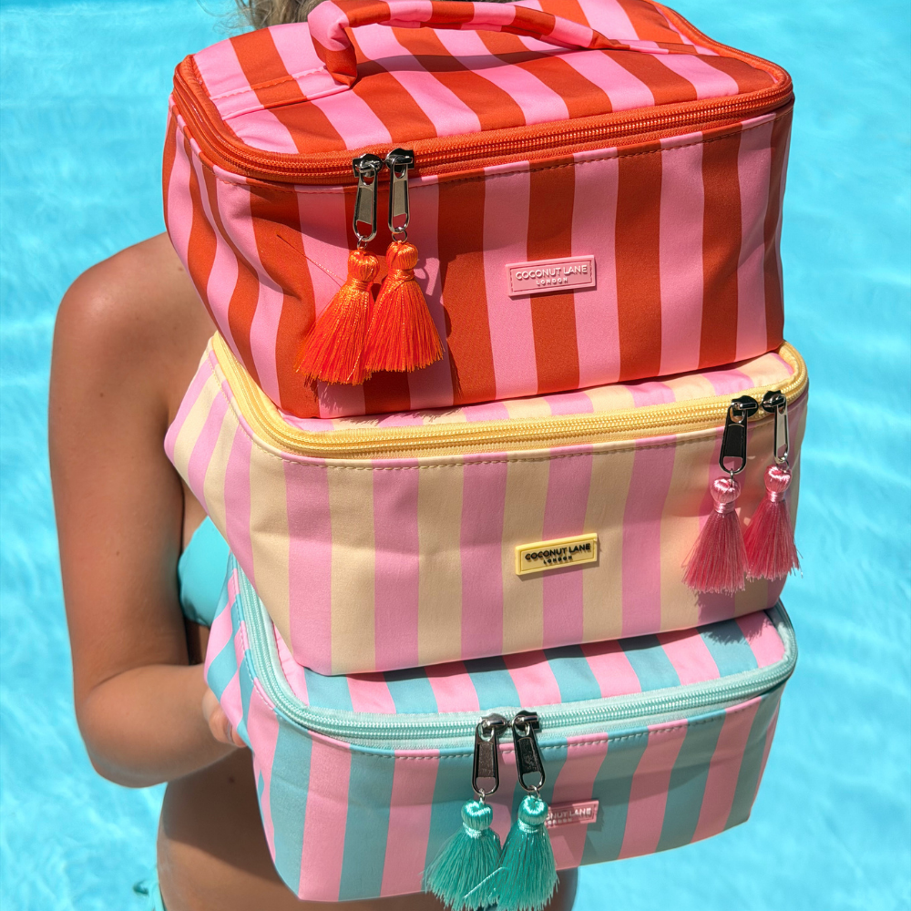 Stack of three striped bags with tassels against a blue water background