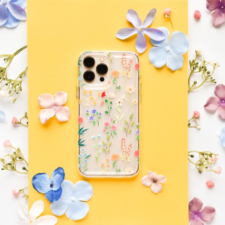A white smartphone with daisy patterns on the back, featuring a prominent camera module, rests on a soft, white fabric background.