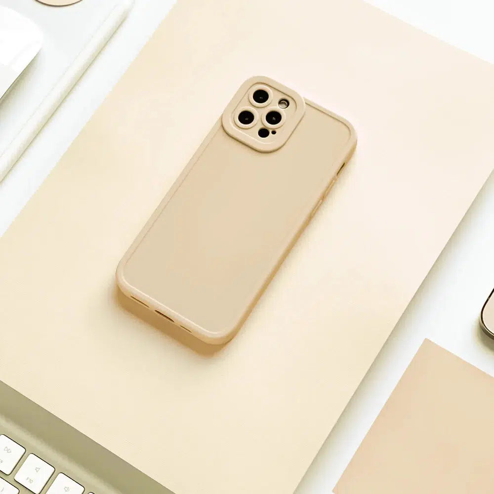 A beige smartphone with a triple-camera setup on a matching neutral-toned surface, surrounded by a white keyboard and part of a laptop. Minimalist and elegant composition.
