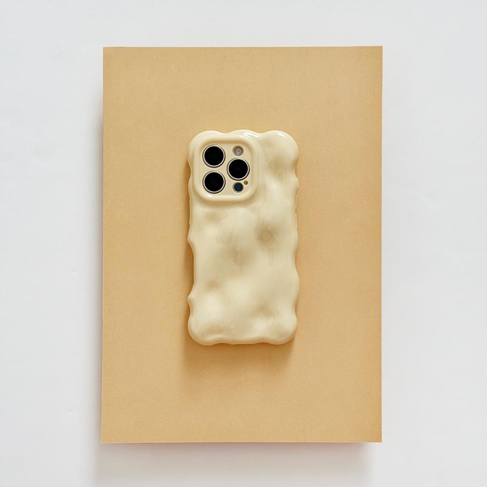 A white smartphone with a wavy, bubble-like case lies on a light surface surrounded by scattered pearls of various sizes. The phone's camera lenses are prominent at the top.