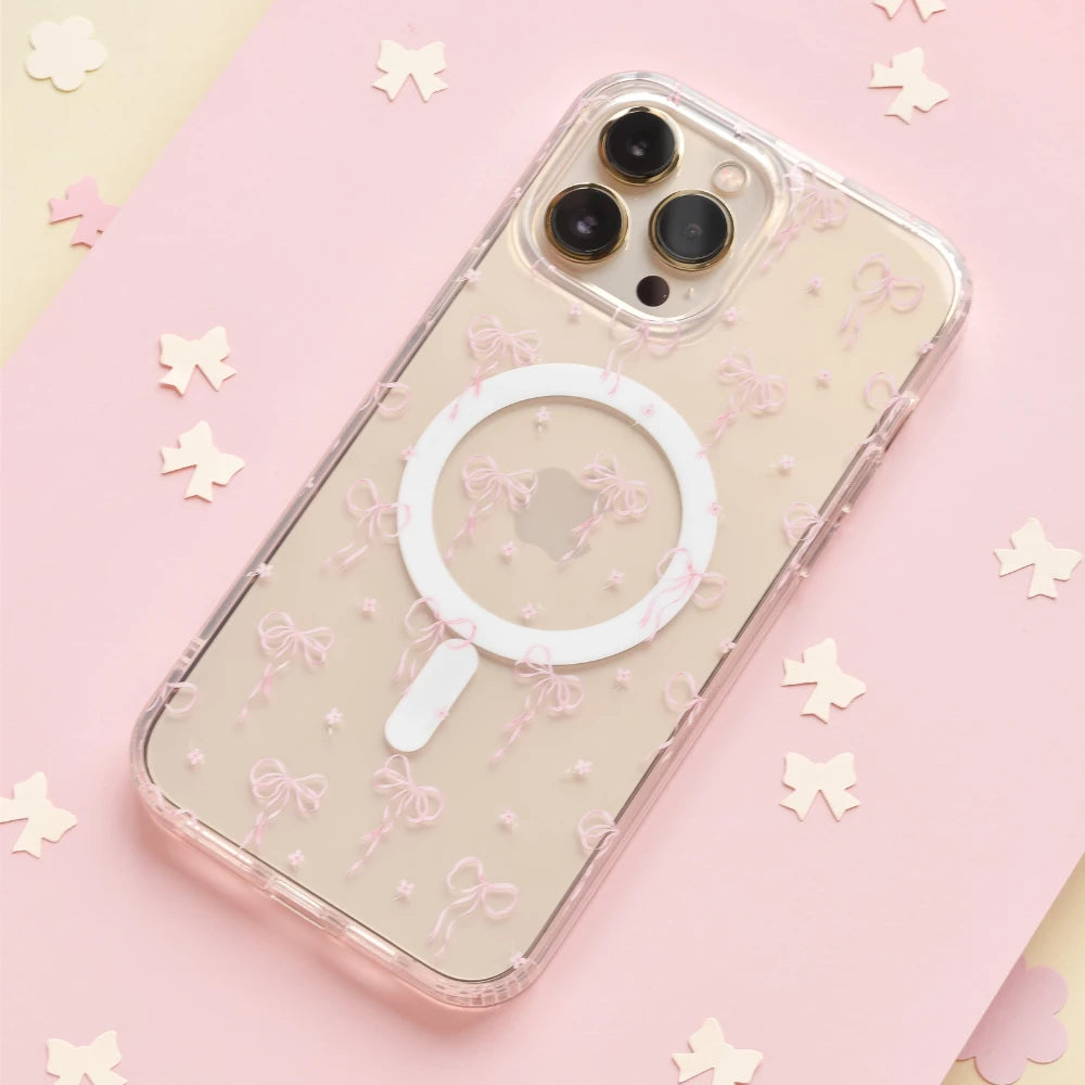 A smartphone with a pink case is wirelessly charging via a circular magnetic charger attached to the back. The phone features triple cameras and a lightning cable plugged into the charger.