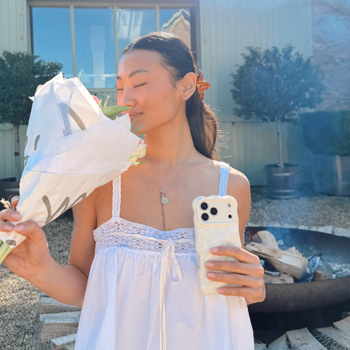 Girl holding flowers next to a fire pit taking a selfie with 3D Bubble Phone Case Cloud Dancer