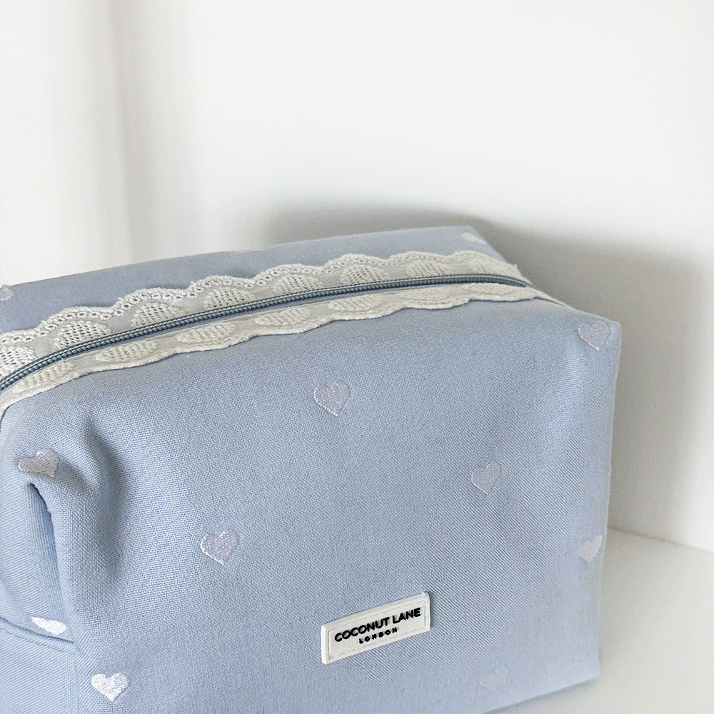 Blue fabric Makeup Bag with embroidered heart design and white lace trim.
