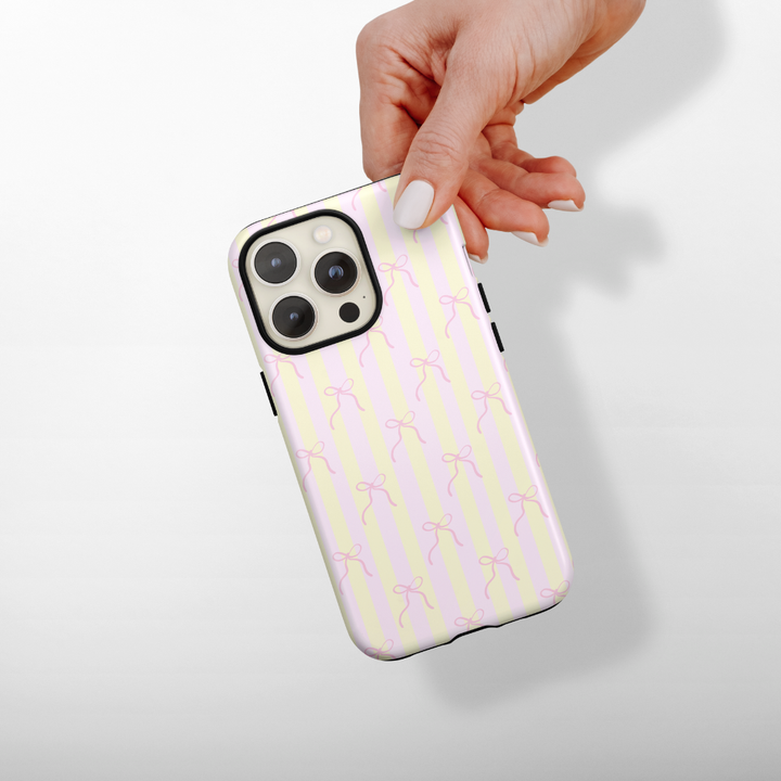 Phone case with pink and yellow striped pattern held by a hand on a white background