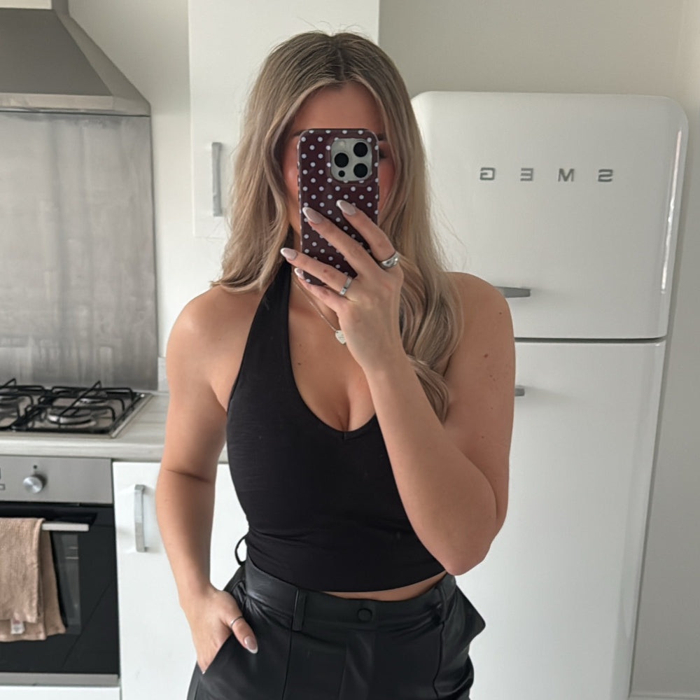 Woman taking a mirror selfie in a kitchen with brown & blue polka dot tough case