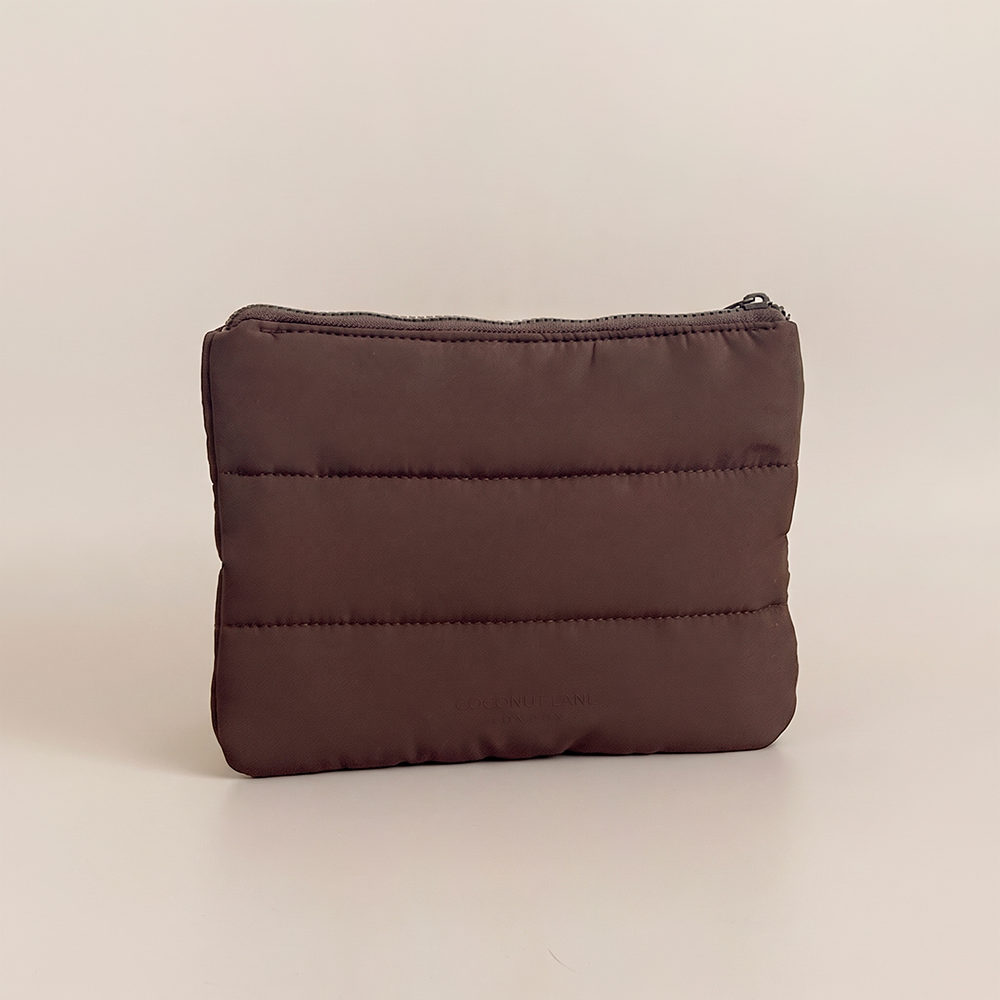 Chocolate brown padded everything pouch with horizontal quilted stitching, zip fastening and subtle Coconut Lane branding on a nude beige background.