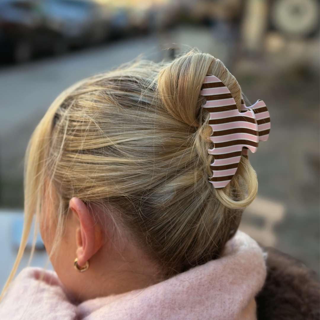 Woman with blonde hair. In her hair is a cocoa and pink stripe Claw Clip featuring glossy chocolate brown, blush pink and cream vertical stripes.