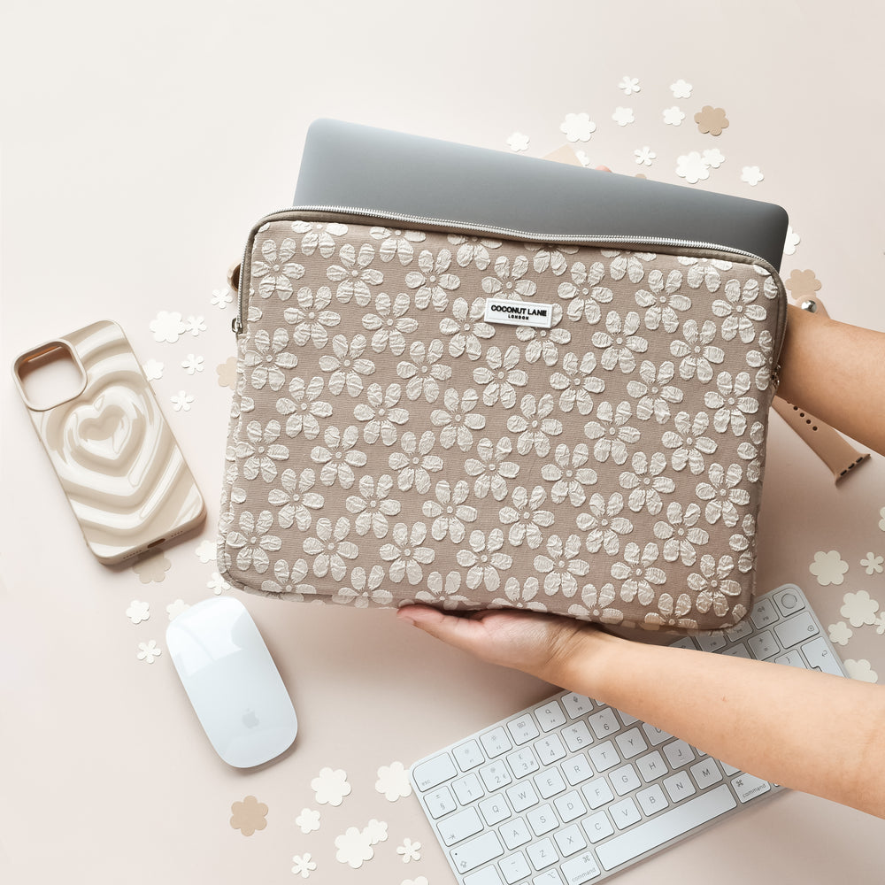 Mocha Flower laptop sleeve with floral pattern beside a keyboard, white mouse, and pink heart phone case.