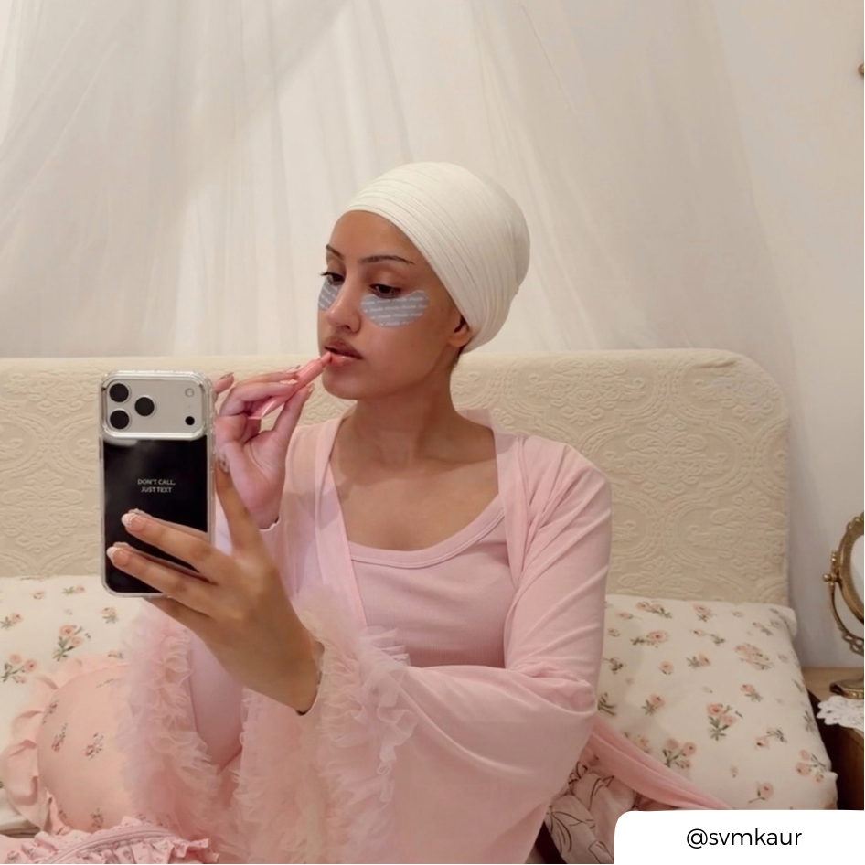 Woman taking a selfie, applying lipbalm, holding an iphone in a mirrored phone case with the text "don't call just text" printed on the back. 