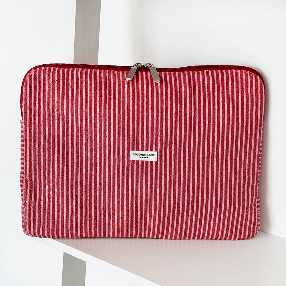 Red and white striped laptop sleeve with zipper, standing upright on a white shelf.