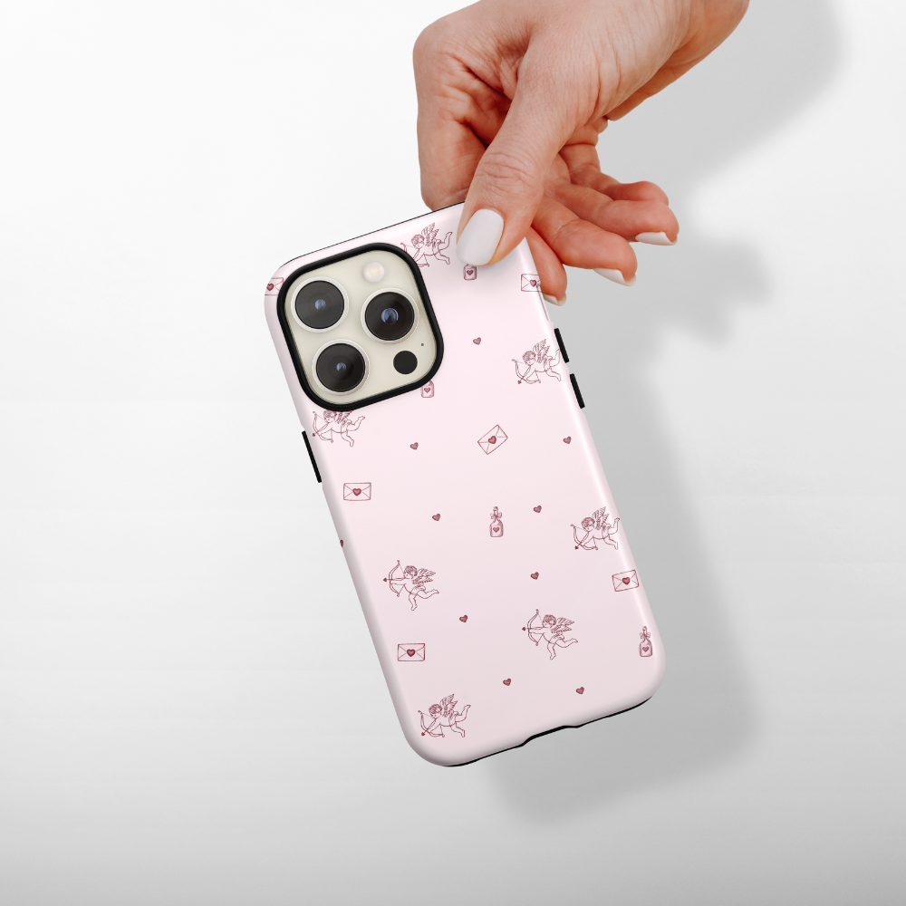 Phone case with a pink cupid and letter design held by a hand on a light gray background