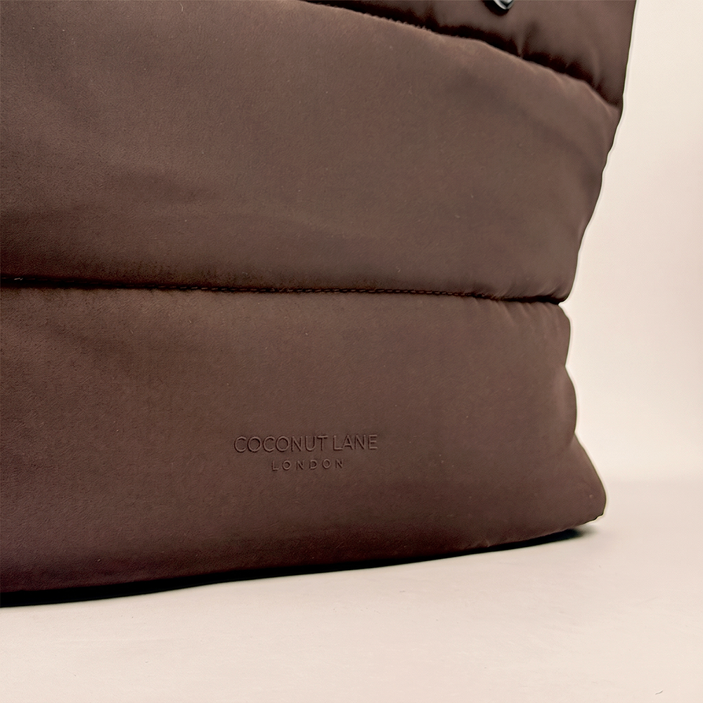 Close-up of the chocolate brown padded carryall bag, highlighting the silicone raised logo.