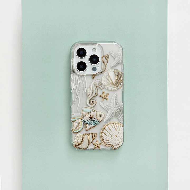 Clear phone case with beaded sea creatures and shells on a light green and white background.