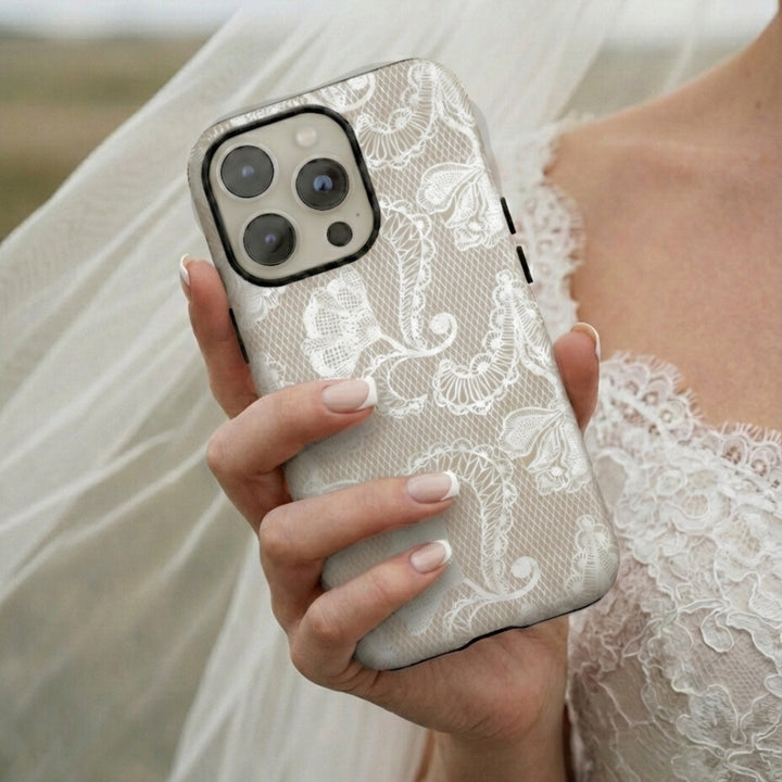 Bride wearing lace holding a phone with a white lace design case