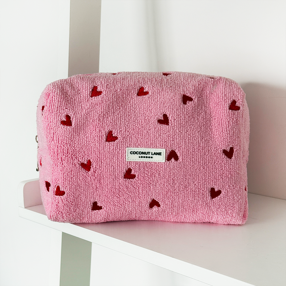 Pink pouch with red heart patterns on a white surface