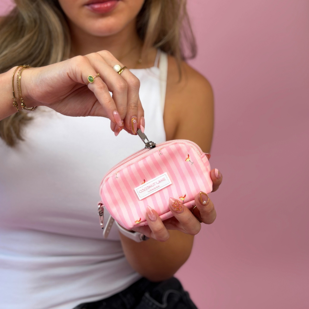 A woman in a white tank top holds a pink striped mini keyring bag. It is decorated with small spicy margarita illustrations. 