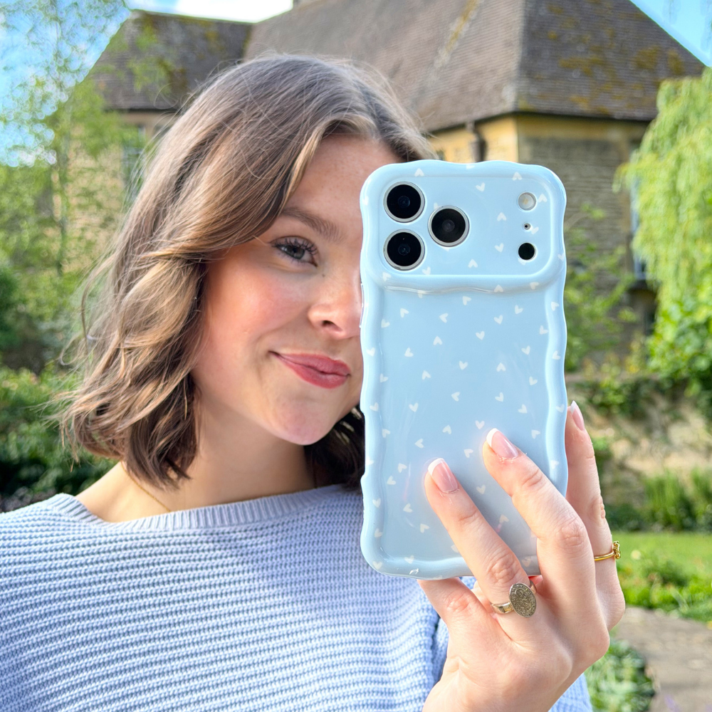 Girl in pretty garden taking selfie with Wavy Phone Case Blue Hearts design