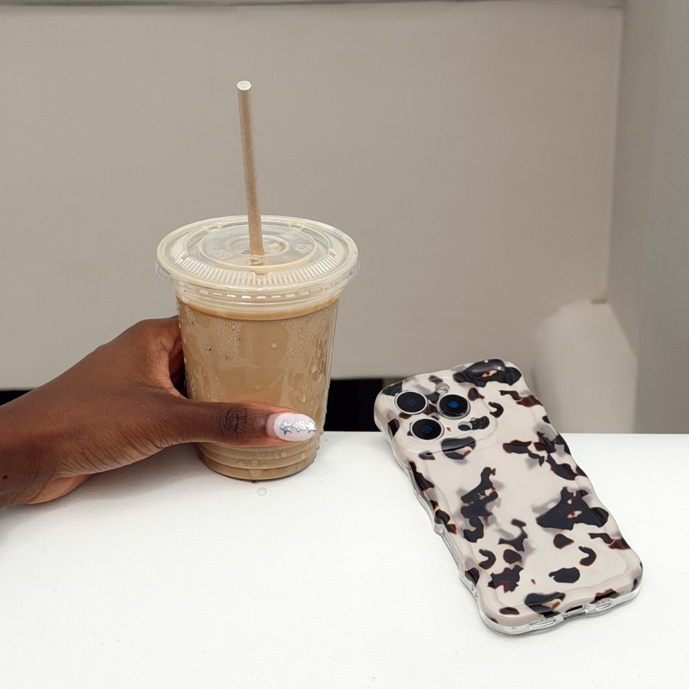 Girl with wavy ivory tort phone case and iced coffee