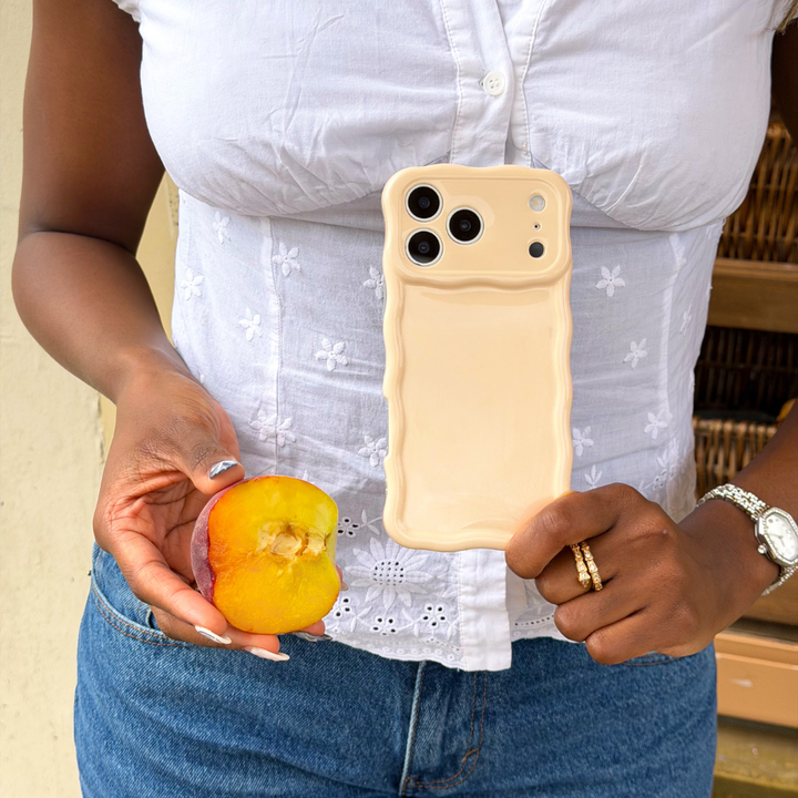 Girl holding her wavy milky peach phone case next to a peach