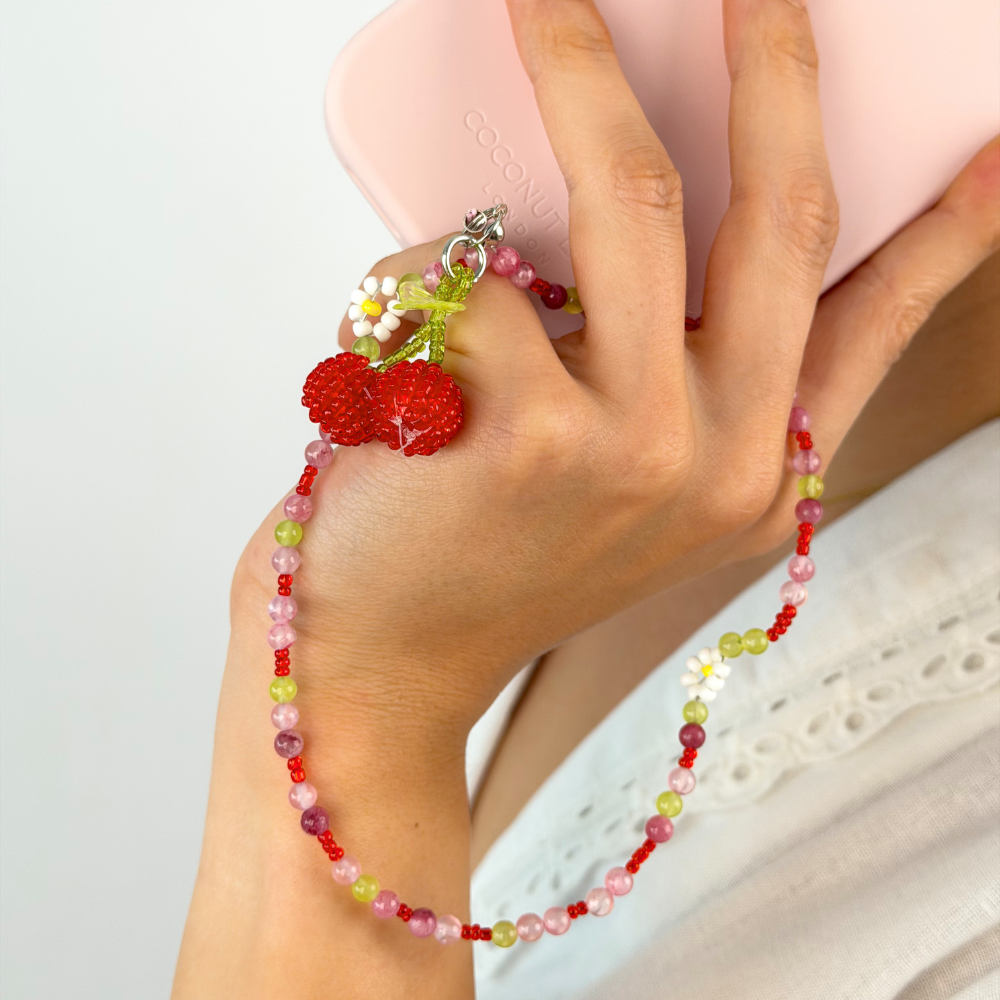 Close up image showing phone strap with cherries and daisy