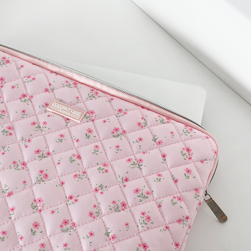White laptop partially in a pink quilted floral sleeve with zipper and visible Coconut Lane brand label.
